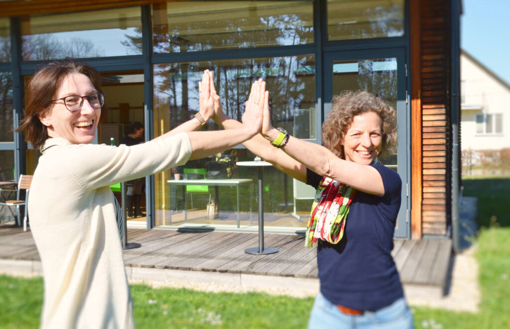 Zwei Frauen stehen sich gegenüber und halten ihre Hände aneinander.