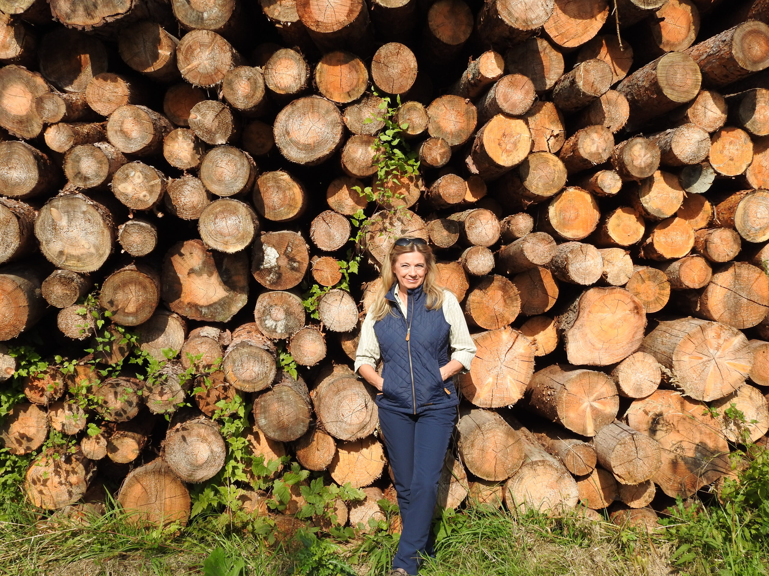 Christa Kummer lehnt an einem Holzstoß.
