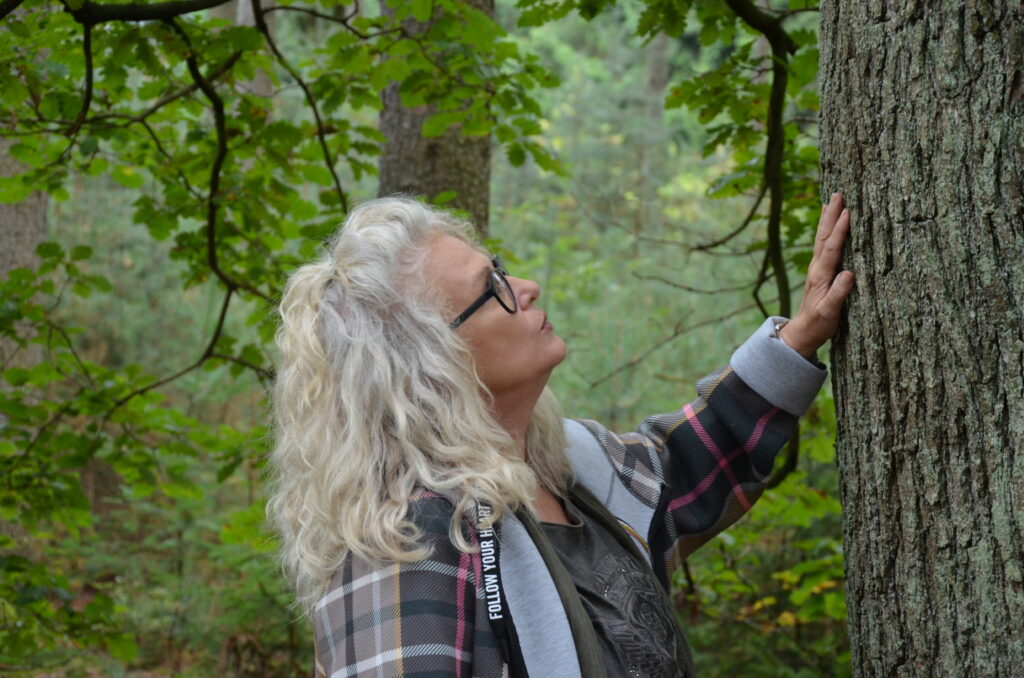 Frau greift im Wald an einen Baumstamm