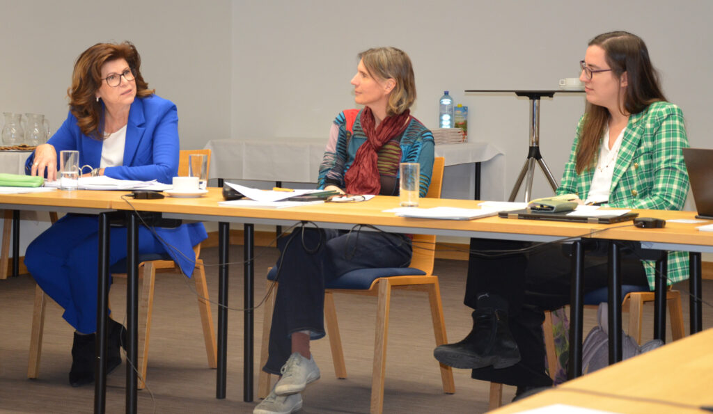 Drei Frauen sitzen an einem Tisch und diskutieren