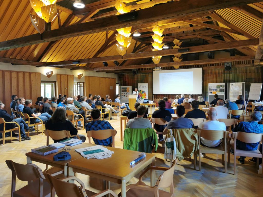 Saal mit mehreren Teilnehmenden und einem Vortragenden beim Hofburggespräch in Gradenbach