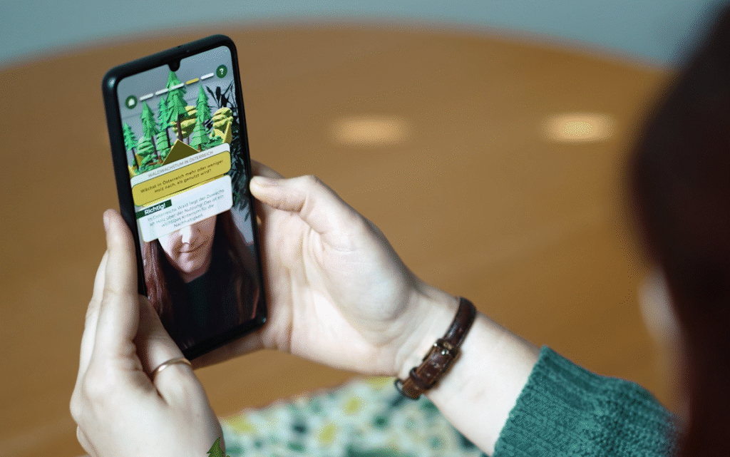 Eine Person hält ein Smartphone in der Hand und beantwortet Quizfragen der App im Selfie-Modus