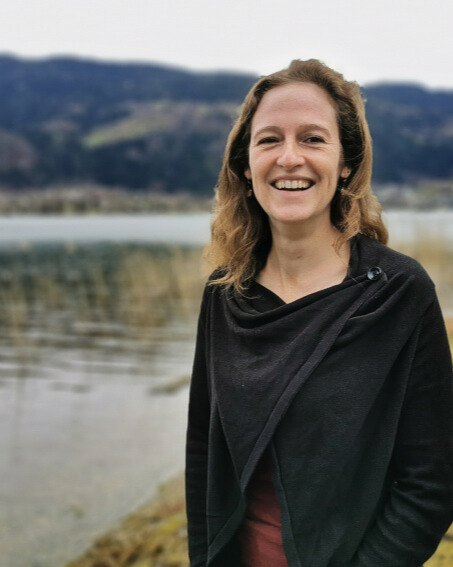 Frau, lachend am Seeufer